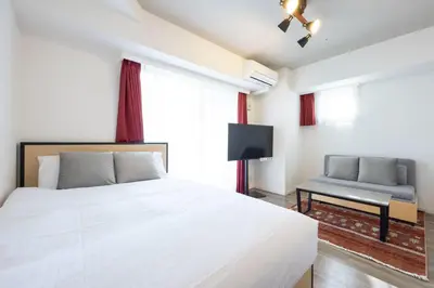 a bedroom with a large white bed and a chair at \u30d7\u30e9\u30fc\u30ba\u30bf\u30ef\u30fc\u6771\u65b0\u5bbf in Tokyo
