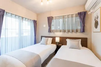 two beds in a room with a window at Bijou Suites Cocoa in Tokyo