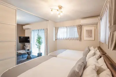 a bedroom with a large white bed and a window at Bijou Suites Cocoa in Tokyo