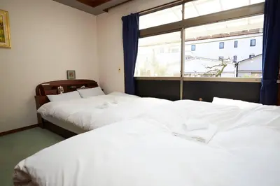 two beds in a room with a window at 東京寓 - Spacious Traditional Home & Zen Garden - For Family&Group up to 8 ppl in Tokyo