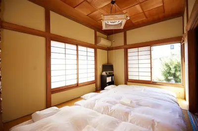 a large bed in a room with two windows at 東京寓 - Spacious Traditional Home & Zen Garden - For Family&Group up to 8 ppl in Tokyo