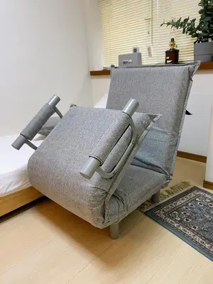 a gray chair with two pillows on a bed at Daily Hotel - \u30a8\u30af\u30bb\u30eb\u4e09\u7530 Excel Mita - \u4e09\u7530\u99c5\u304b\u3089\u5f92\u6b695\u5206 in Tokyo