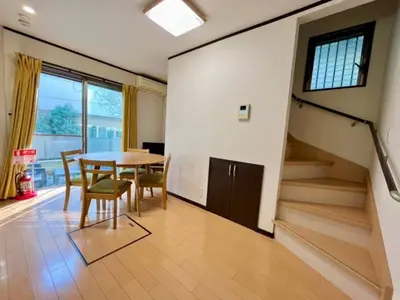 a dining room with a table and chairs and a staircase at Saitore in Tokyo