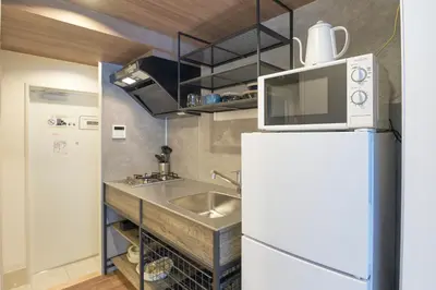 a kitchen with a sink and a microwave on top of a refrigerator at MATSUMIZAKA Hill by Tranova in Tokyo