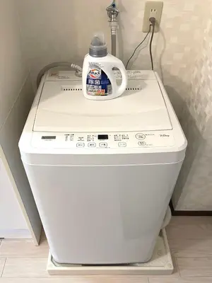 a washing machine with a bottle of laundry detergent on top at Near\u65b0\u5bbf Safy Room in Tokyo