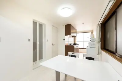 a white kitchen with a white table and chairs at Masaya setagaya in Tokyo