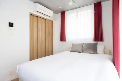 a bedroom with a large white bed with red curtains at Lega land\u5e61\u30f6\u8c37ANNEX in Tokyo