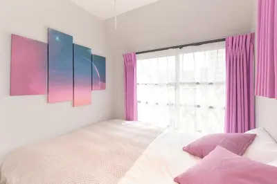 a bedroom with a bed and a window with pink curtains at Blighton Miyoshi by Tranova in Tokyo