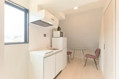 a kitchen with a small table and a white refrigerator at Blighton Miyoshi by Tranova in Tokyo