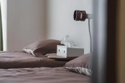 a bed with a alarm clock and a lamp on it at LT Shinjuku West in Tokyo