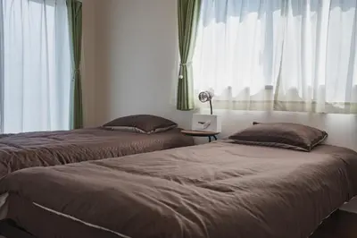 two beds in a bedroom with curtains and a table at LT Shinjuku West in Tokyo