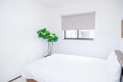 a white bedroom with a plant in a vase on a bed at Family Inn Hikifune in Tokyo