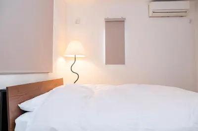 a bedroom with a white bed and a lamp at Family Inn Hikifune in Tokyo