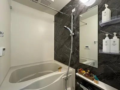 a bathroom with a tub and a shower with a mirror at nestay inn tokyo ueno in Tokyo