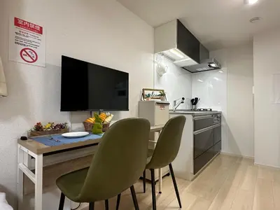 a kitchen with a table with two chairs and a television at nestay inn tokyo ueno in Tokyo
