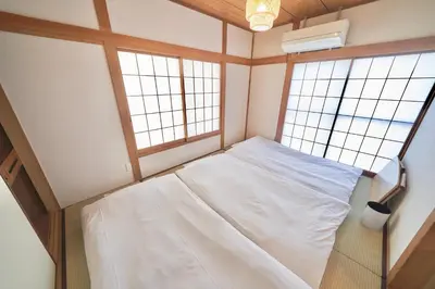 a small room with a bed and two windows at TOMARIE Residential Suite Higashi-Tateishi in Tokyo