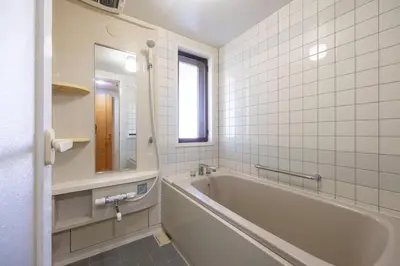 a white tiled bathroom with a tub and a window at DeLCCS\u9ad8\u5186\u5bfa in Tokyo