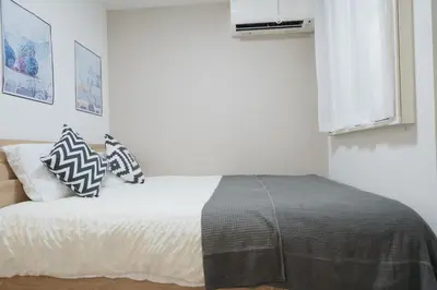 a bedroom with a bed with white sheets and pillows at \u4e00\u4e2a\u4eba\u65c5\u884c \u897f\u65b0\u5bbf\u7ad9\u6b65\u884c8\u5206 \u65b0\u5bbf\u7ad9\u5f92\u6b6516\u5206 JR\u5c71\u624b\u7ebf\u65b0\u5927\u4e45\u4fdd\u7ad9\u6b65\u884c15\u5206 \u514d\u8d39WiFi in Tokyo