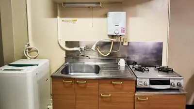a kitchen with a sink and a stove and a refrigerator at \u683c\u5b89\u6c11\u5bbf \u65e5\u66ae\u91cc\u99c5\u304b\u3089\u5f92\u6b694\u5206 \u9280\u5ea7 \u4e0a\u91ce\u76f4\u901a in Tokyo
