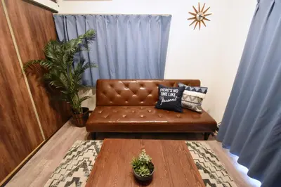 a brown leather couch in a living room with blue curtains at Shinozaki Kodate - Vacation STAY 16392 in Tokyo