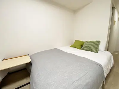 a small bedroom with a bed and a wooden table at The Lions in Tokyo