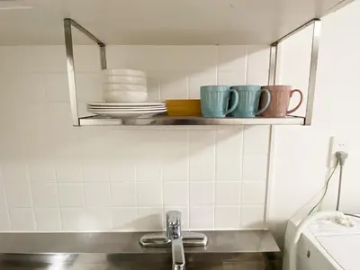 a kitchen with cups and plates on a shelf at The Lions in Tokyo