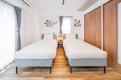 two beds in a room with wooden floors and windows at Zaito Tokyo East Mukojima APT in Tokyo