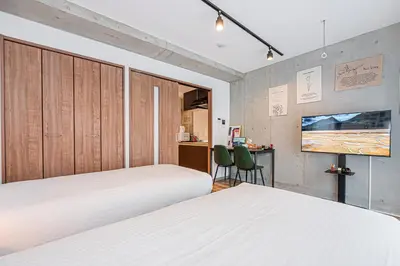 a bedroom with two beds and a desk and a tv at Zaito Tokyo East Mukojima APT in Tokyo