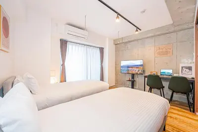 a bedroom with two beds and a desk with a computer at Zaito Tokyo East Mukojima APT in Tokyo