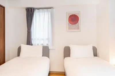 two twin beds in a room with a window at Zaito Tokyo East Mukojima APT in Tokyo