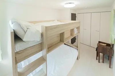 a large wooden bunk bed in a white room at \u732b\u597d\u304d i HOTEL SkyTree\u307e\u306714\u5206 \u6700\u592710\u4eba \u65b0\u7bc9 \u4e00\u6238\u8cb8 WiFi\u5b8c\u5099 \u6d17\u6fef\u4e7e\u71e5\u6a5f \u99d0\u8eca\u5834\u4e8c\u53f0\u5206 in Tokyo