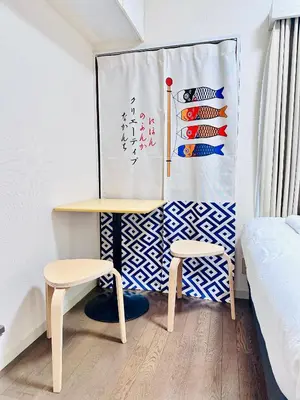a table and two stools in a room with a wall at Amadeus 21 in Tokyo