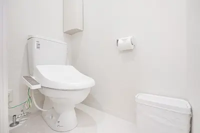 a white bathroom with a toilet and a roll of toilet paper at ZAITO Tokyo PRETIC Hikifune in Tokyo
