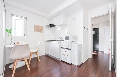 a white kitchen with a table and a microwave at ZAITO Tokyo PRETIC Hikifune in Tokyo