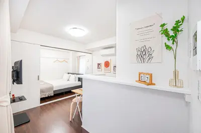 a small white room with a bed and a desk at ZAITO Tokyo PRETIC Hikifune in Tokyo