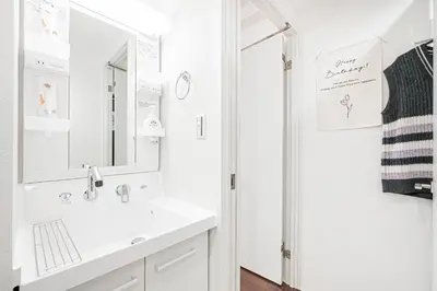 a white bathroom with a sink and a mirror at ZAITO Tokyo PRETIC Hikifune in Tokyo