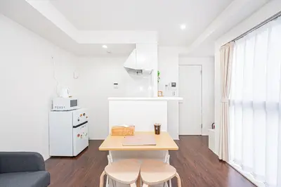 a kitchen and living room with a table and two stools at ZAITO Tokyo PRETIC Hikifune in Tokyo