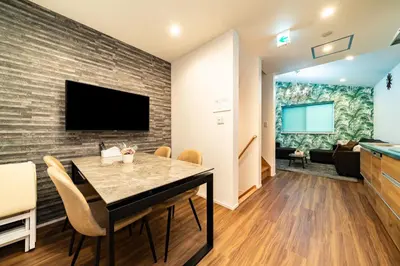 a dining room with a table and a tv on a brick wall at 89, Yahiro 1, Detached House for Rent, \u516b\u5e831 in Tokyo