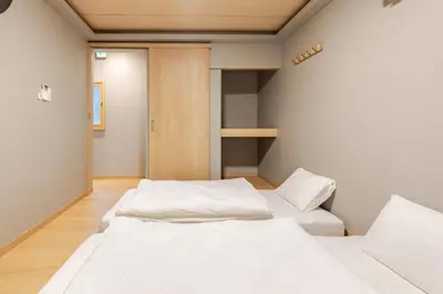 a room with two beds and a door to a closet at \u65b0\u5bbf6 Home in Tokyo