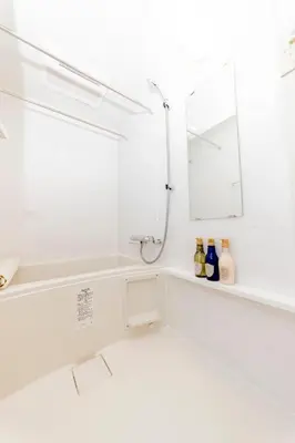 a white bathroom with a tub and a mirror at FL Residence Shinjuku Gyoen V in Tokyo