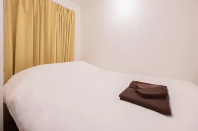 a white bed with a brown purse on it at \u30b8\u30a7\u30df\u30cb\u30b9\u6c60\u888b203 in Tokyo
