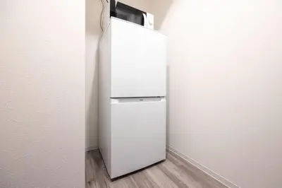 a white refrigerator in a corner of a room at ARUCiA\u99d2\u6ca2\u5927\u5b66 in Tokyo