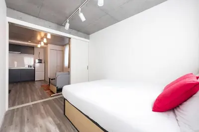 a bedroom with a white bed with red pillows at ARUCiA\u99d2\u6ca2\u5927\u5b66 in Tokyo