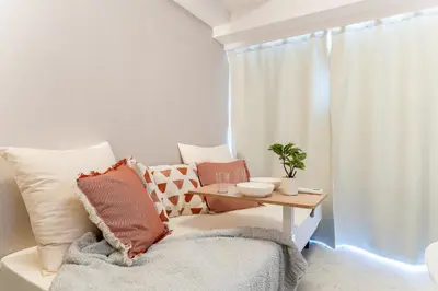 a living room with a table and a couch with pillows at Galicia Otsuka in Tokyo