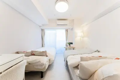 a white room with two beds and a couch at Galicia Otsuka in Tokyo