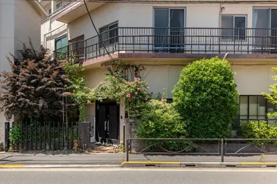 an apartment building with a gate and flowers in front of it at Villa Katsushika\u304a\u82b1\u8336\u5c4b\u99c5\u5f92\u6b6910\u5206 in Tokyo