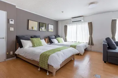 a bedroom with two beds and a couch at Ryusen Panda Hotel Noda in Tokyo