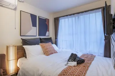 a bedroom with a white bed with a large window at Ryusen Panda Hotel Noda in Tokyo