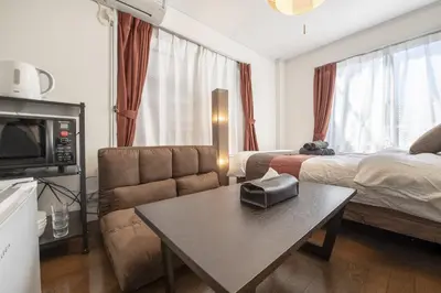 a living room with a bed and a couch and a table at Ryusen Panda Hotel Noda in Tokyo