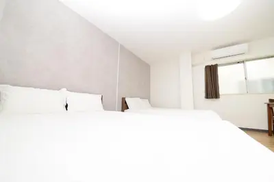 a white bedroom with two beds and a window at \u548c\u306e\u6953cottage\u7b2c\u4e8c302 \u65b0\u5bbf\u6b4c\u821e\u4f0e\u753a\u8fd1\u96a3 in Tokyo